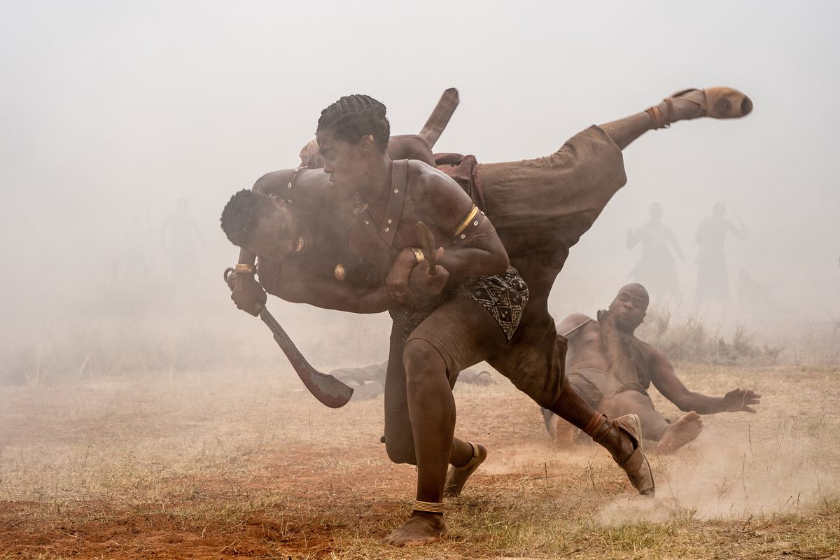 The warrior Izogie (Lashana Lynch) throws a male warrior to the ground during a battle in The Woman King