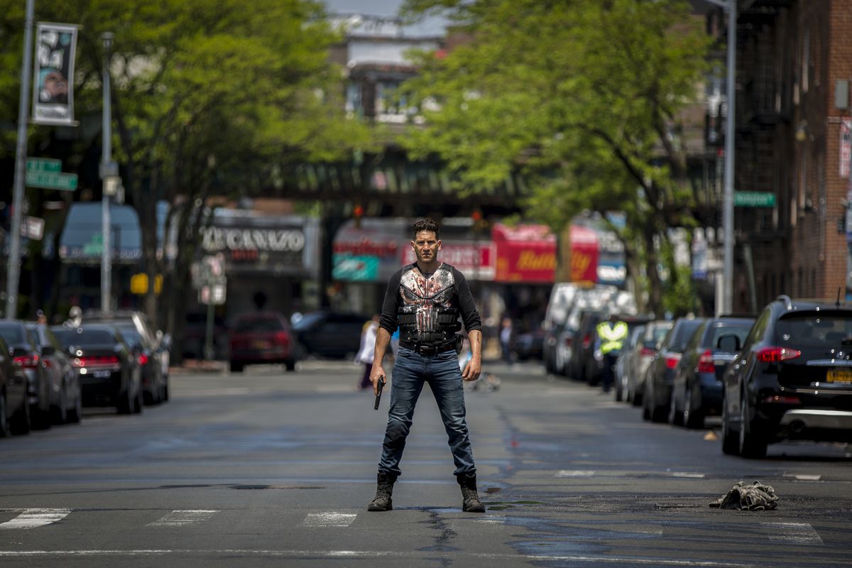 Jon Bernthal as The Punisher standing in the middle of a New York street with a bloody t-shirt