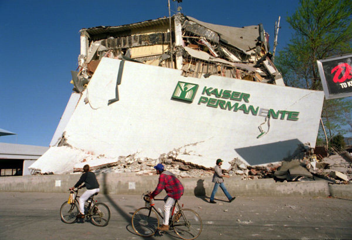 Los ciclistas pasan junto a los restos de una clínica y un edificio de oficinas de Kaiser Permanente que se derrumbó.