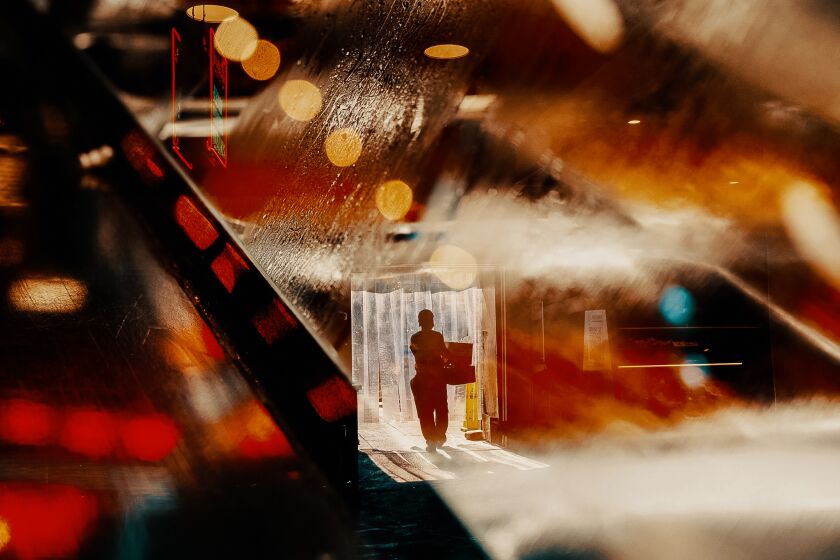 عرض مزدوج لرجل يحمل صناديق بأضواء Grand Central Market في وسط مدينة لوس أنجلوس. / بيثاني مولينكوف لصحيفة لوس أنجلوس تايمز