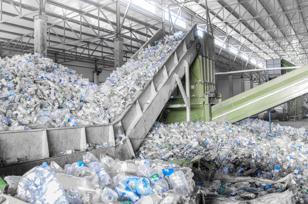 صورة مقربة للسلالم المتحركة مع كومة من الزجاجات البلاستيكية في المصنع للمعالجة وإعادة التدوير.