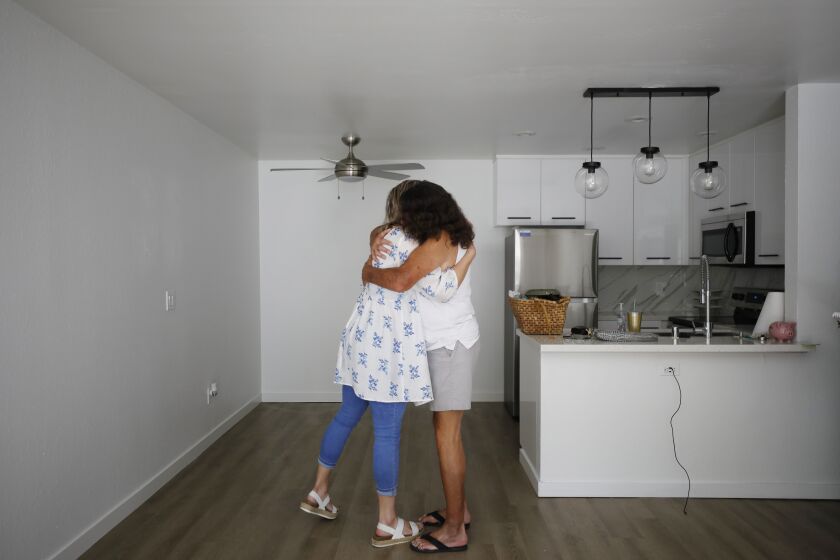 SAN DIEGO, CA - 19 DE SEPTIEMBRE: Hope Shaw, especialista en vivienda de PATH (Personas que ayudan a las personas sin hogar) abraza a Bruce Blackham en su nuevo apartamento que organizó el lunes 19 de septiembre de 2022 en San Diego, CA. Se utilizó un vale de vivienda de emergencia financiado por la Ley del Plan de Rescate Estadounidense para asegurarle un apartamento. (KC Alfred / The San Diego Union-Tribune)
