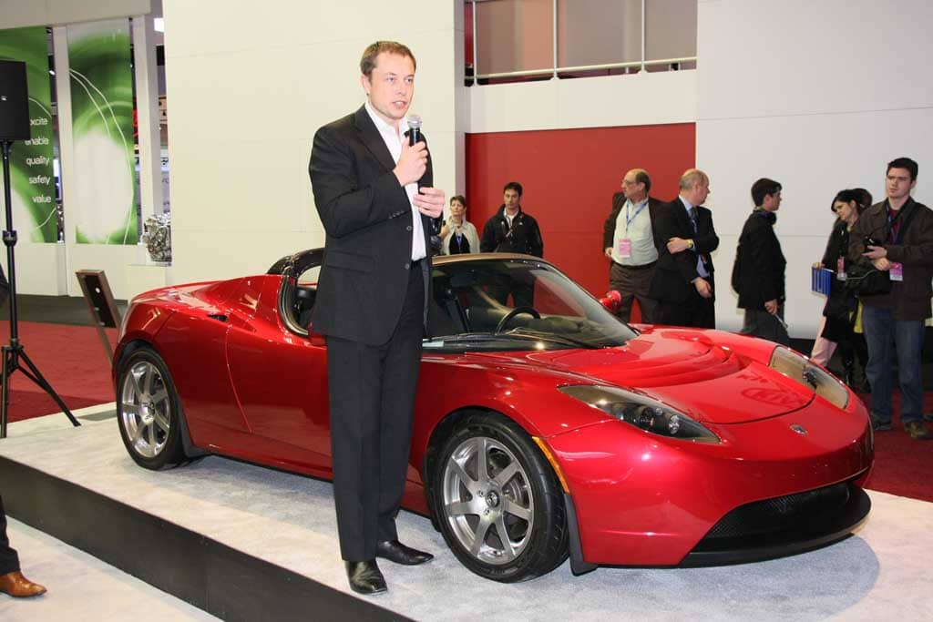 Tesla Motors'un kurucusu Elon Musk, burada Tesla Roadster ile birlikte gösteriliyor.