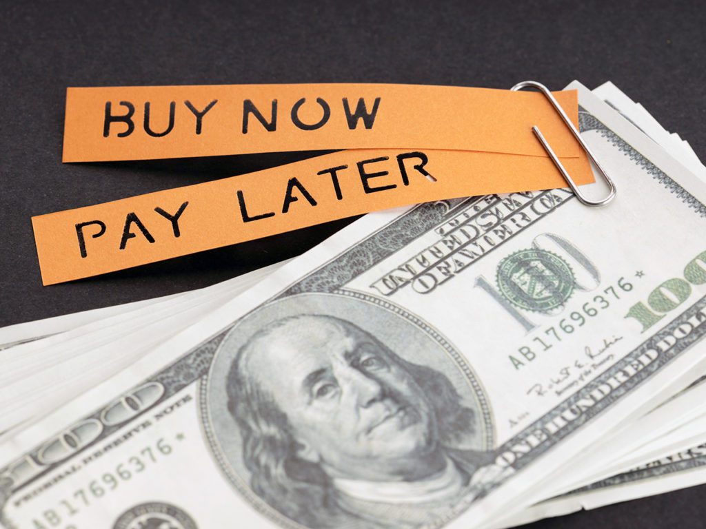 BNPL of Buy Now Pay Later-concept. Dollarbiljetten en label met bericht op zwarte achtergrond