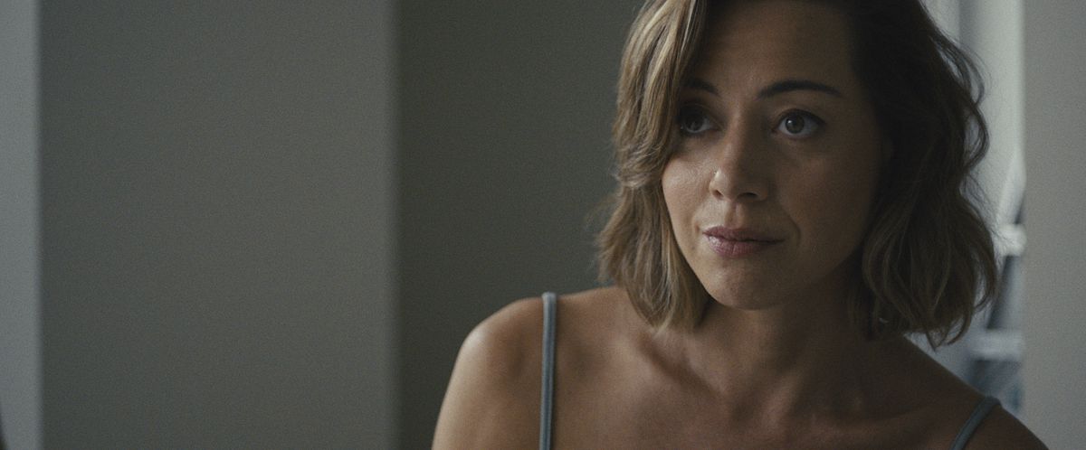 Aubrey Plaza stares defiantly past the camera with a slight smirk on her face in Emily the Criminal