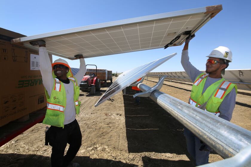 LEMOORE CA 24 JUNI 2021 - Van links naar rechts plaatsen Rayshawn Lee en Omar Lemus panelen op de bouwplaats van Westlands Solar Park, dat na voltooiing een van de grootste zonneparken in het land zal zijn in Lemoore, Californië, donderdag , 24 juni 2021. (Gary Kazanjian/For The Times)
