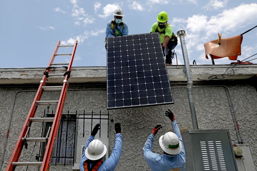 Werknemers van GRID Alternatives, een non-profitorganisatie, installeren zonnepanelen bij een huis met een laag inkomen in Watts