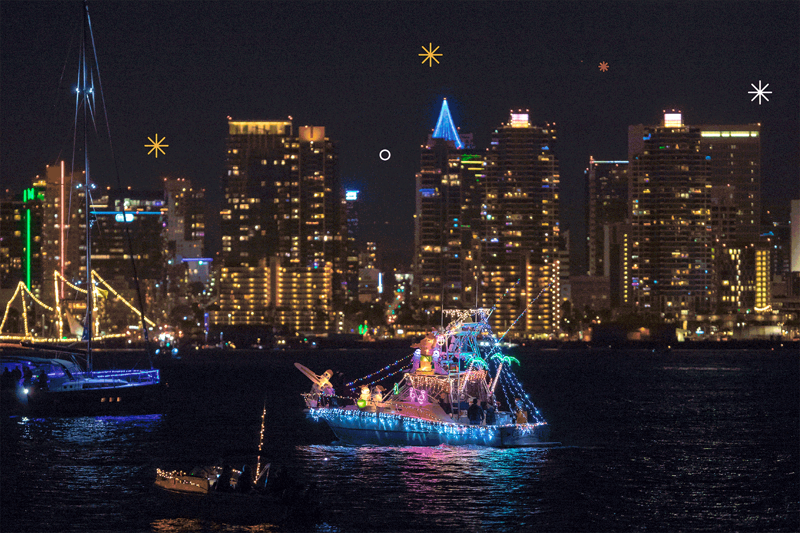 Zeilboten, jachten en rubberboten verlichten San Diego Bay tijdens de 48e jaarlijkse San Diego Bay Parade of Lights. Geanimeerd vuurwerk verlicht de lucht.
