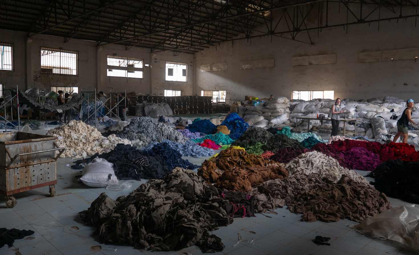 Honderden tonnen kleding sorteren in een verlaten fabriek.