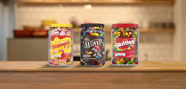 Starburst, M&M's and Skittles plastic candy jars on a counter
