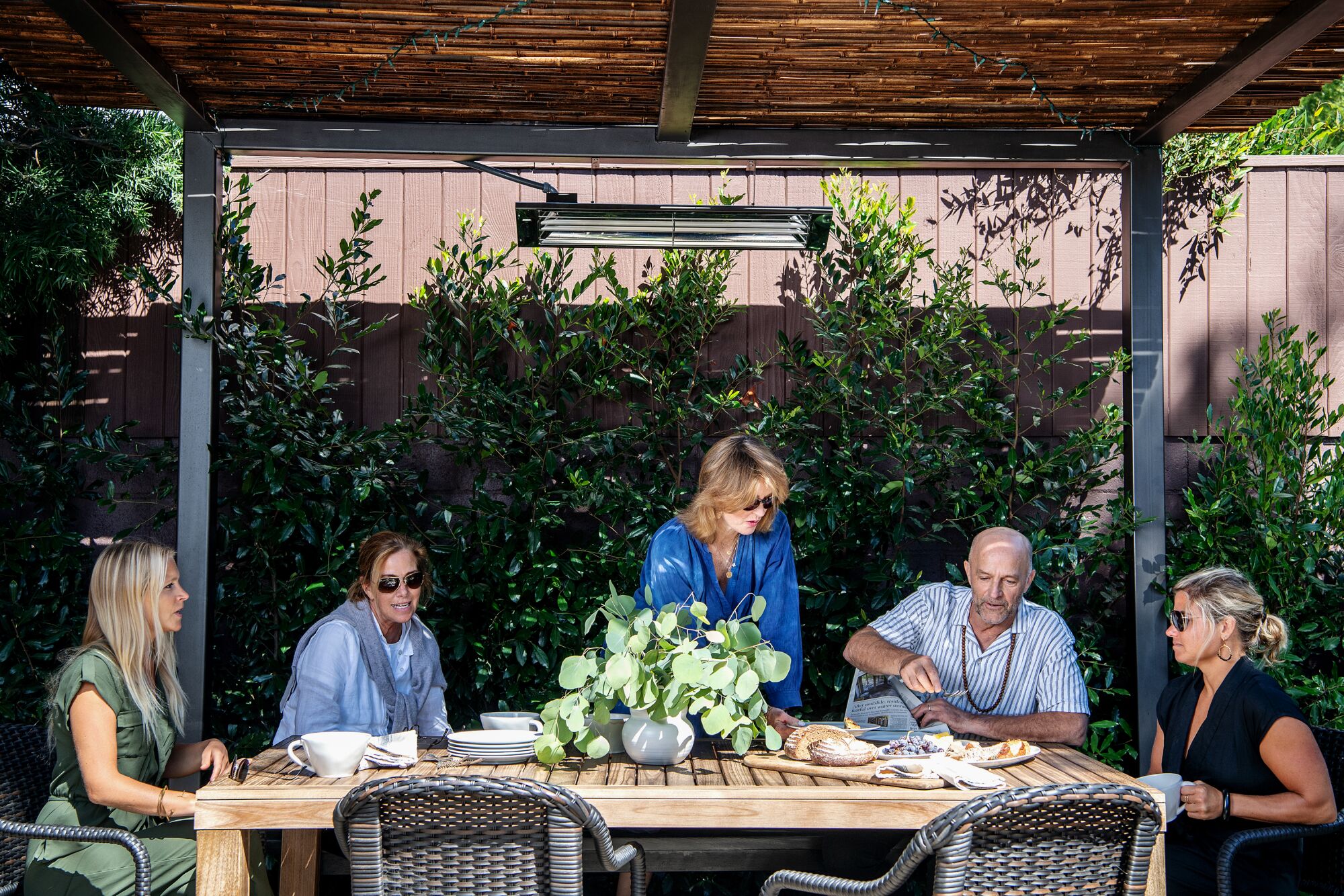 Un grupo de personas se sienta en una mesa de comedor al aire libre.