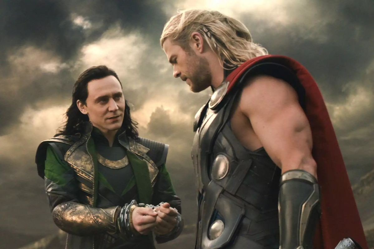 Tom Hiddleston as Loki displays his bound wrists to Chris Hemsworth as Thor in Thor: The Dark World
