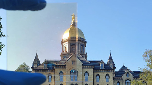 La Cúpula Dorada de Notre Dame fotografiada parcialmente a través de una muestra (arriba a la izquierda) del revestimiento de la ventana de TRC.