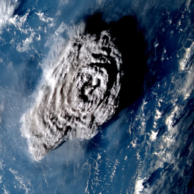 통가 화산 폭발 100분 후. Hunga Tonga-Hunga Ha'apai 화산의 분출을 위에서 찍은 확대 사진으로 검푸른 바다를 배경으로 보는 사람을 향해 버섯처럼 피어오르는 회색 깃털을 보여줍니다.