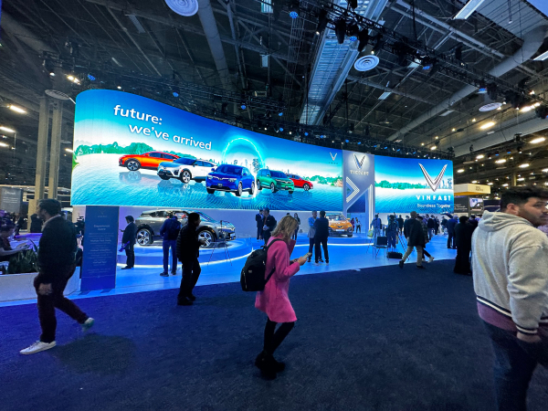 The VinFast booth at CES 2023, with vehicles on display in the background and attendees in the foreground