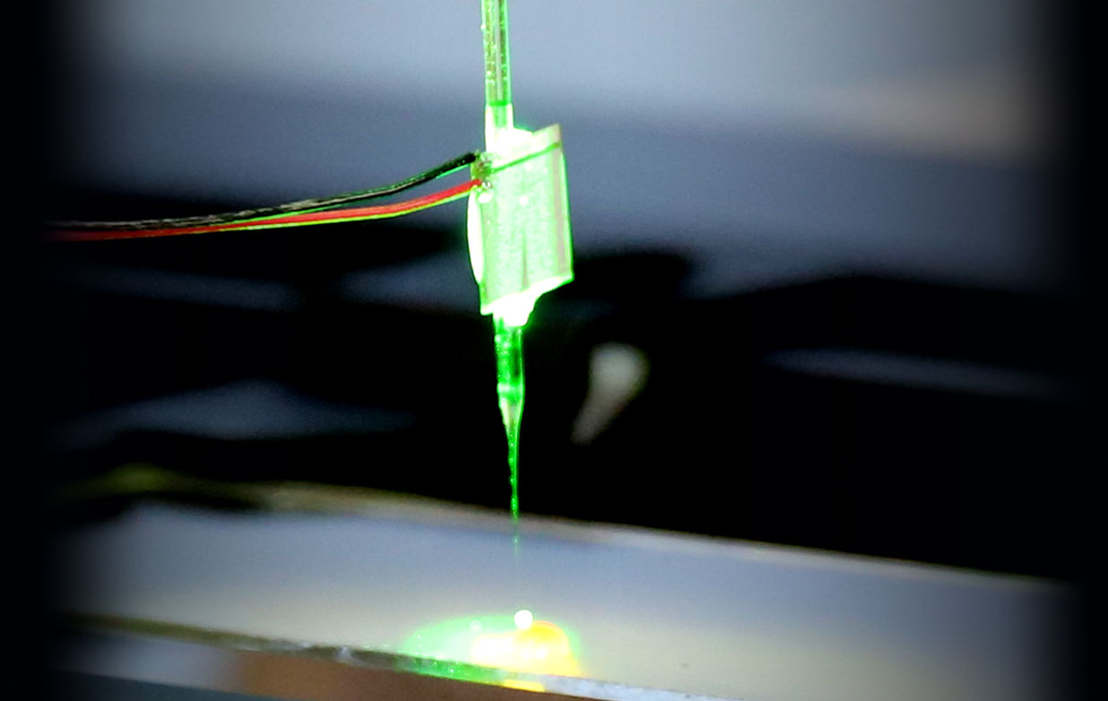 The glass needle that captures the particles glows neon green