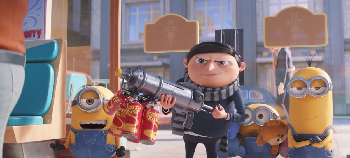 Young Gru, backed by Minions, holds up a gun powered by “cheezy blast” spray cans in Minions: The Rise of Gru