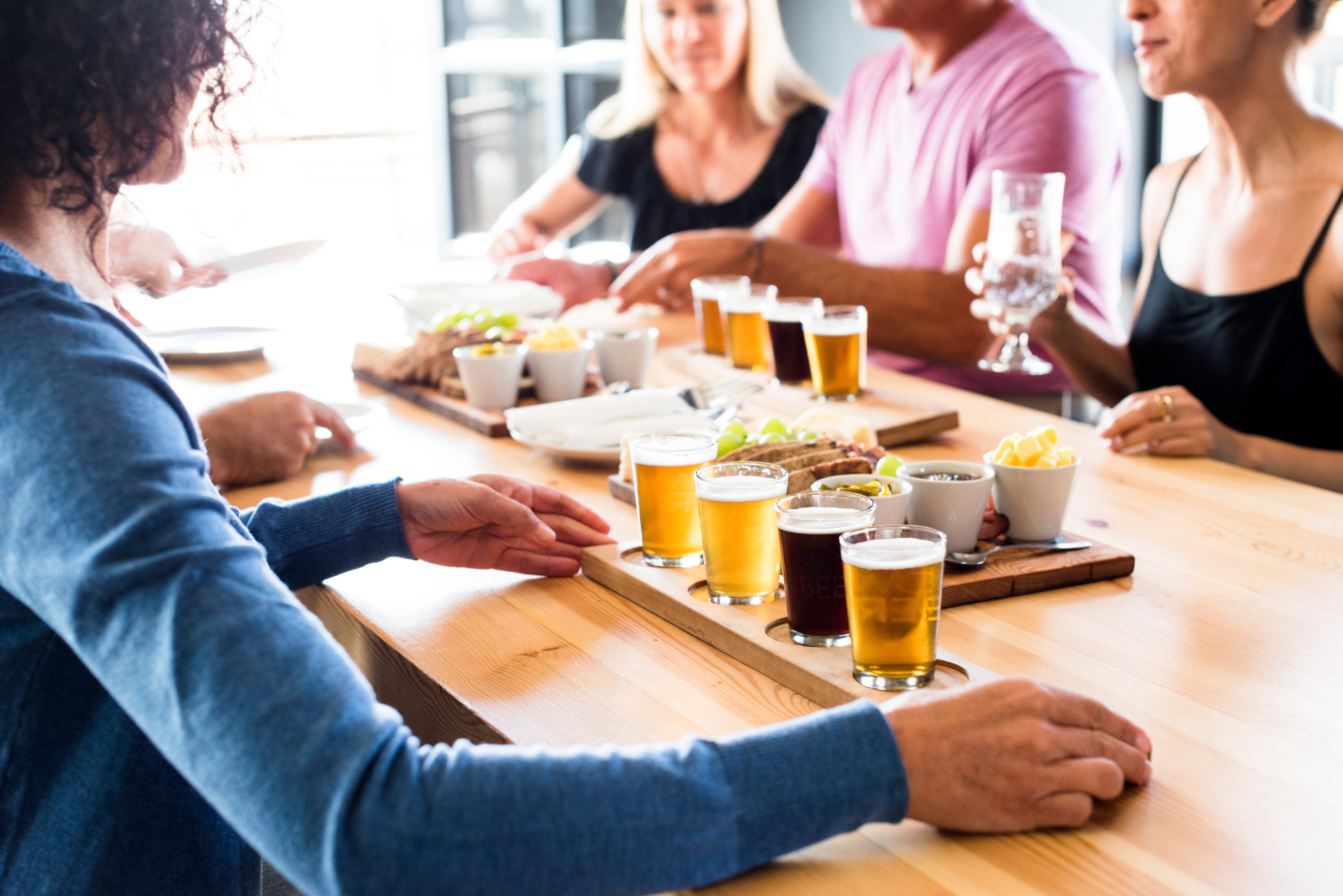 Friends sitting at a dining table with appetizers and beer flights 