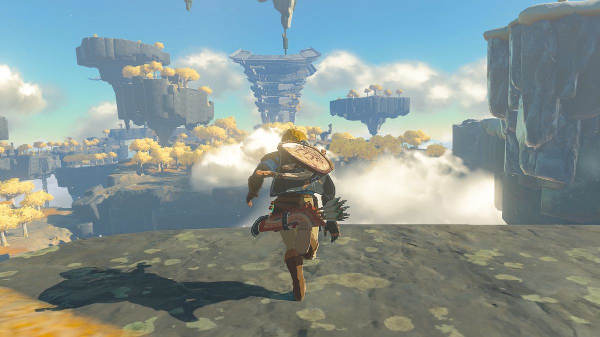 Link corre hacia el borde de una plataforma rocosa, con formaciones rocosas flotantes al fondo, en una captura de pantalla de The Legend of Zelda: Tears of the Kingdom.