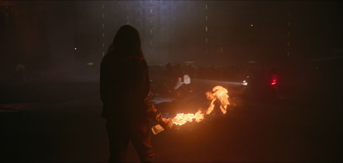يقف شخصية مظللة تحمل زجاجة مولوتوف مشتعلة في شوارع باريس في أثينا