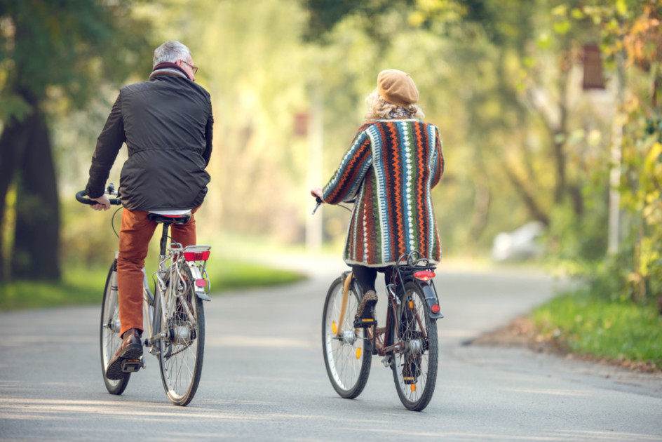 Vista trasera de una pareja montando en bicicleta en el parque.