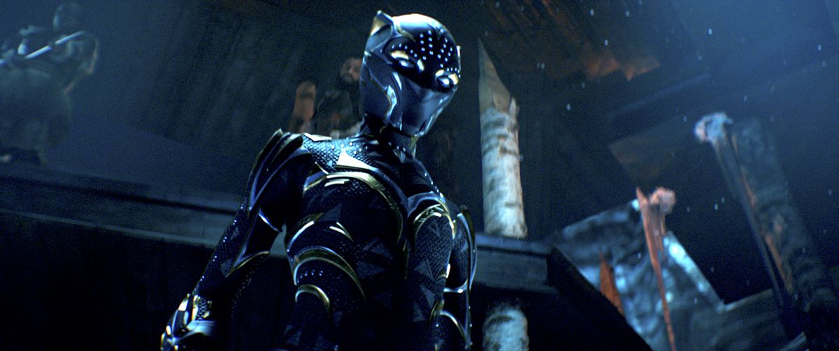 Shuri i sin guldstrimmiga Black Panther-kostym, stående i ett mörkt tronrum, i Black Panther: Wakanda Forever