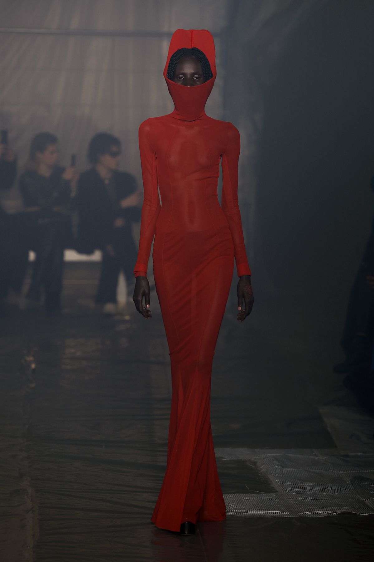 A model wearing a bright red dress with a hood walks the runway at the Han Kjobenhavn fashion show at Milan Fashion Week.