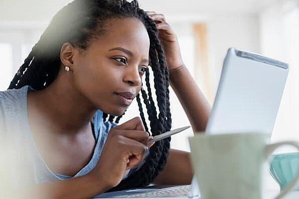 Een vrouw die een pen vasthoudt, staart naar haar laptop terwijl ze probeert te achterhalen of haar bedrijf op een zwarte lijst voor e-mail staat.