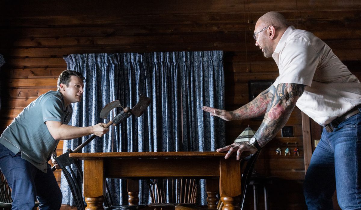 Eric (Jonathan Groff) ve Leonard (Dave Bautista), Knock at the Cabin'deki bir dövüşte avantaj elde etmek için bir masanın etrafında birbirlerinin etrafında dönüyorlar.