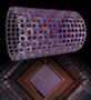 An illustration of the structure of the quantum magnet that was simulated by the D-Wave quantum processor and the processor that simulated it. The quantum magnet looks like a lattice of coloured balls (representing atoms) arranged in a hollow tube. The processor looks like a computer chip.