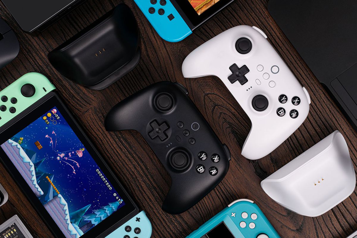 The 8BitDo Ultimate Bluetooth in black and white are shown next to Nintendo Switch consoles.
