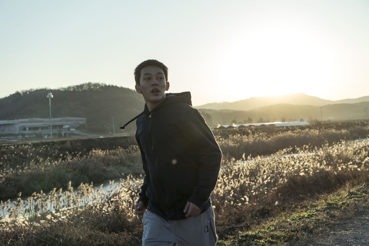 Jong-su (Yoo Ah-in) đi lang thang trên một cánh đồng.