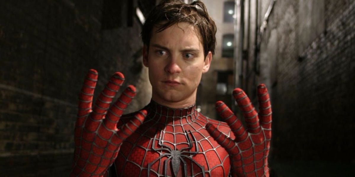 Tobey Maguire als Spider-Man die naar zijn handen kijkt met zijn masker af