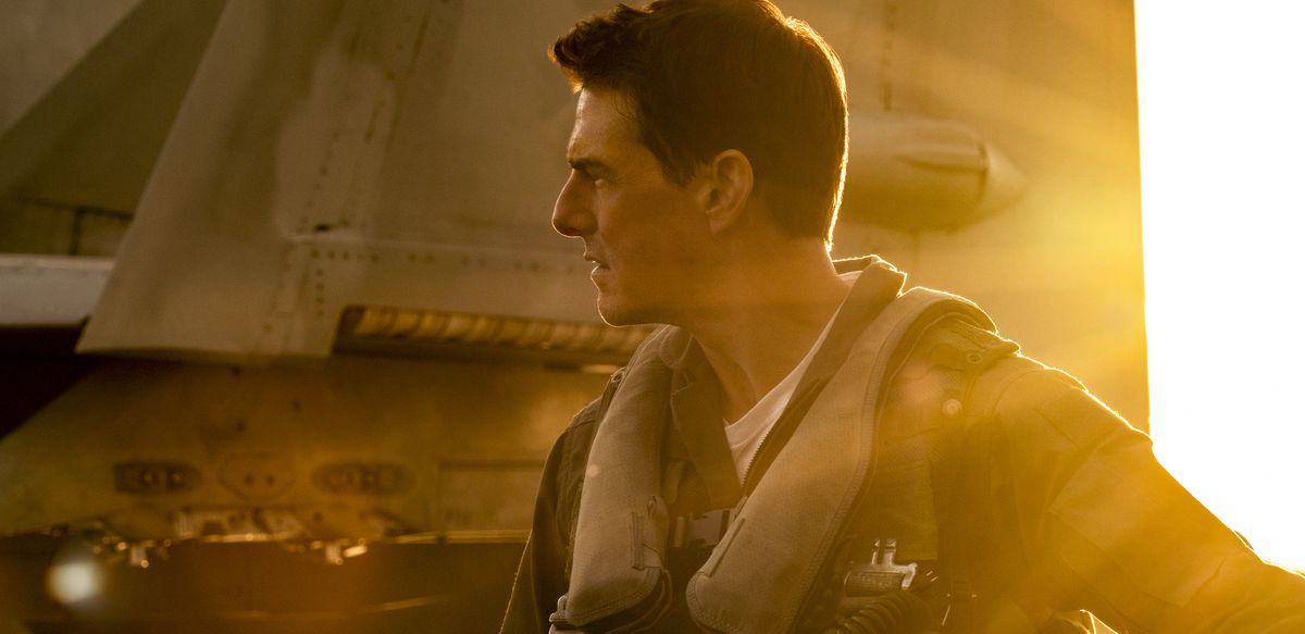 Tom Cruise는 Pete "Maverick" Mitchell 역을 맡아 Top Gun: Maverick에서 전투기 꼬리 부분 앞에 황금빛 햇살을 받으며 서 있습니다.