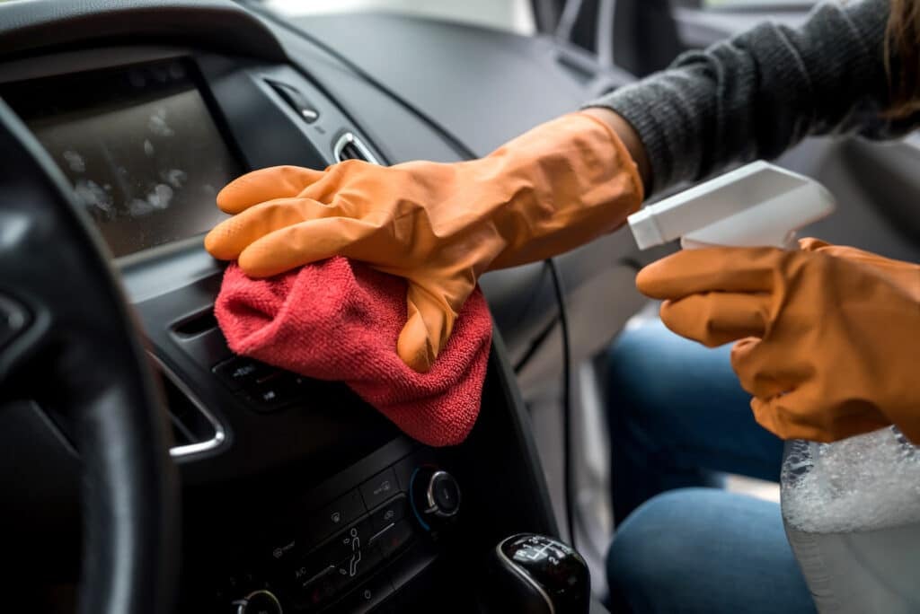 trabajador mano usar guante limpieza interior del coche para la prevención covid-19