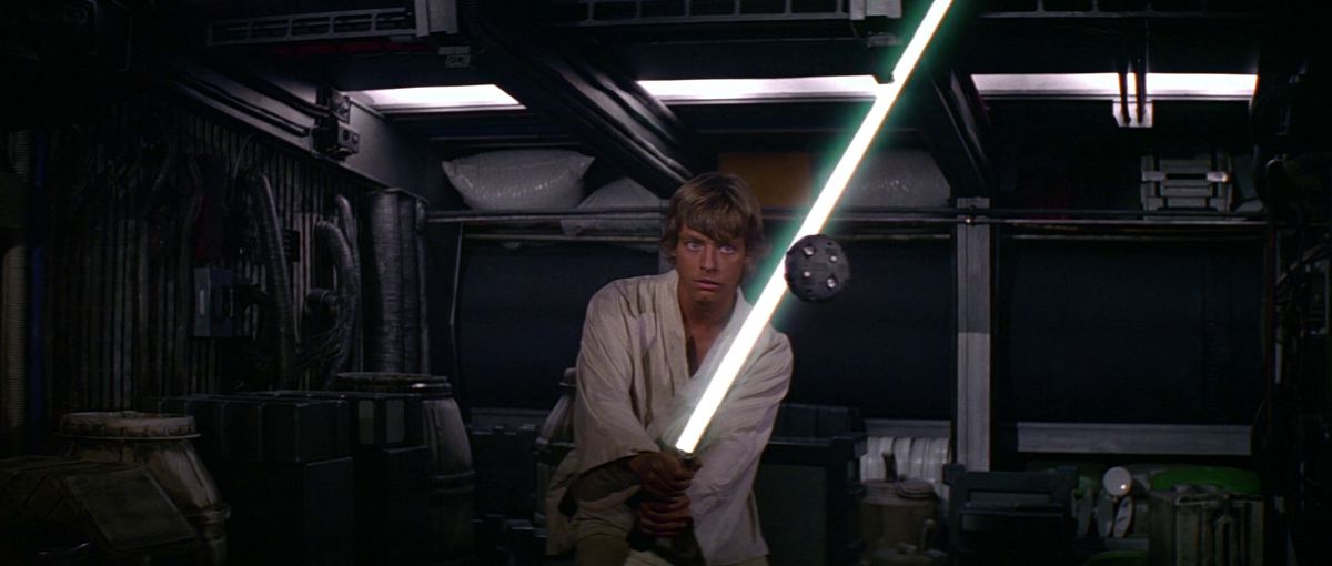 Luke Skywalker, Yeni Bir Umut'ta ışın kılıcını bir eğitim insansız hava aracına doğru tutuyor.