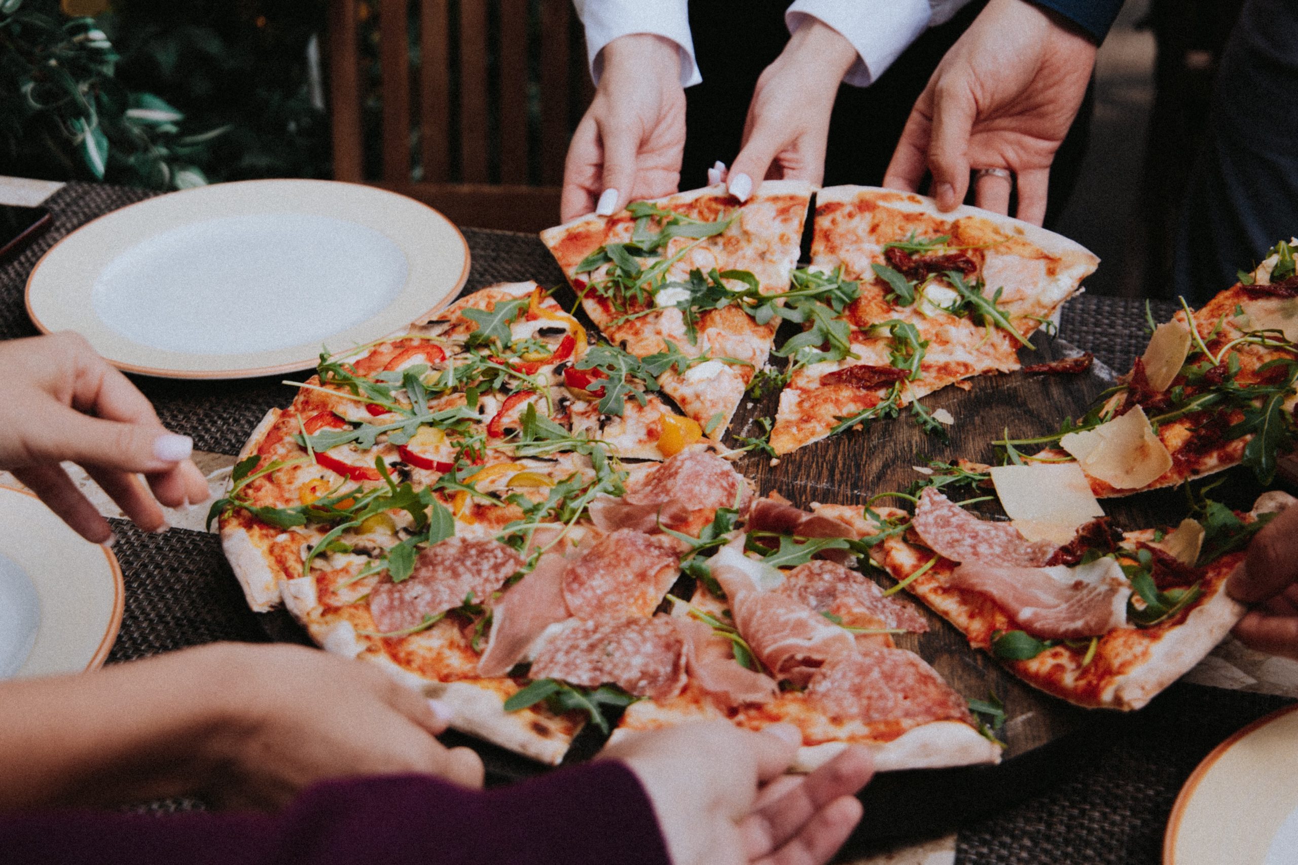 persona sosteniendo pizza en plato de cerámica blanca. 30 de los mejores recaudadores de fondos de alimentos