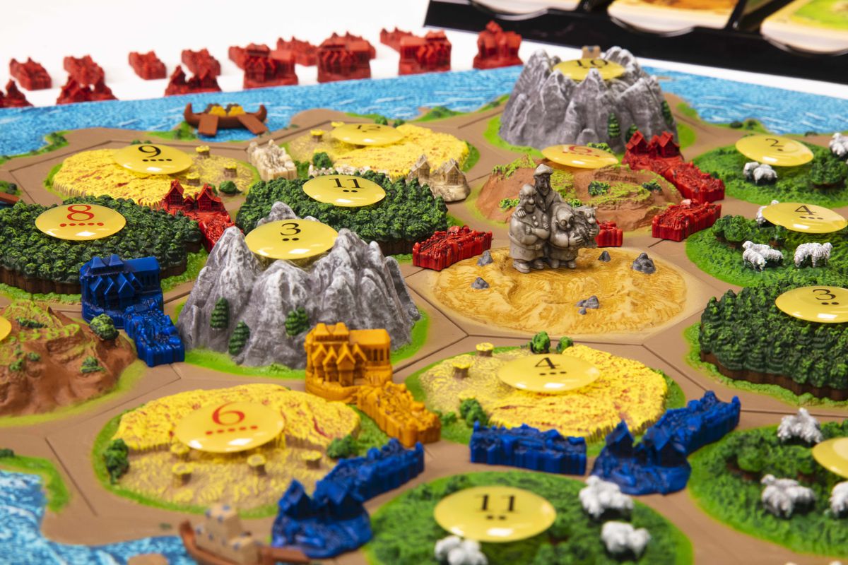 A game of Catan 3D laid out for play, with a massive mountain and a series of plains in the foreground.