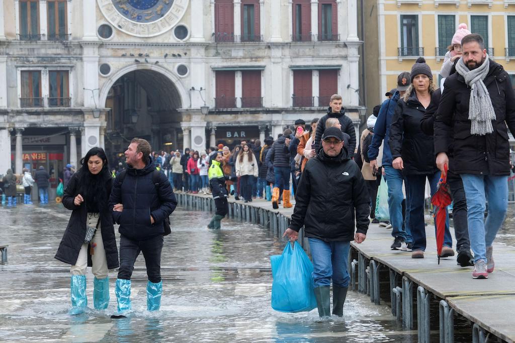 10 Aralık 2022'de Venedik, İtalya'da mevsimsel yüksek su sırasında insanlar sular altında kalan San Marco Meydanı'nda suda yürüyor.