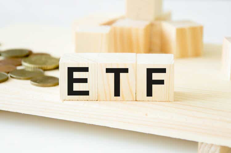ETF - 木製の立方体、立方体、背景にあるコイン上のファンドの証券取引所のテキスト