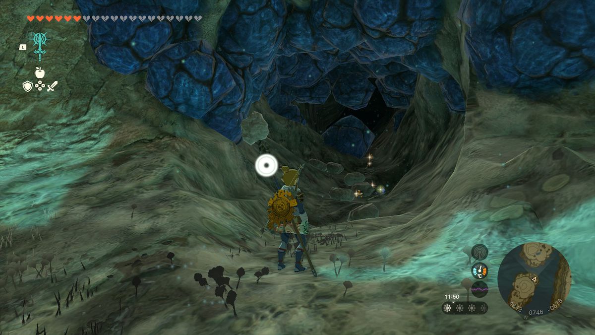 Link, Zelda Tears of the Kingdom'da Depths'te bir grup ganimetin yanında duruyor.