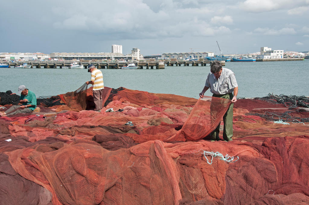 2014年XNUMX月、ポルトガルのペニシェで漁網を直す男性たち。