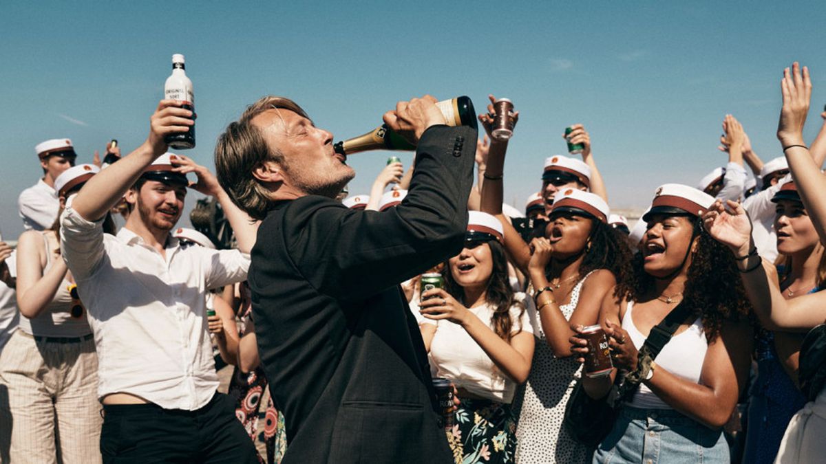 một đám đông cổ vũ điên mikkelsen khi anh ta uống từ một cái chai