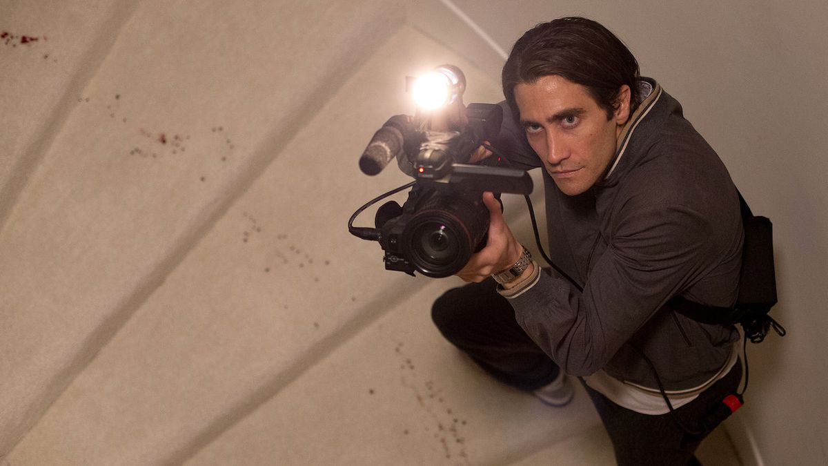 Jake Gyllenhaal como Louis "Lou" Bloom apuntó una cámara hacia arriba de un tramo de escaleras en Nightcrawler.