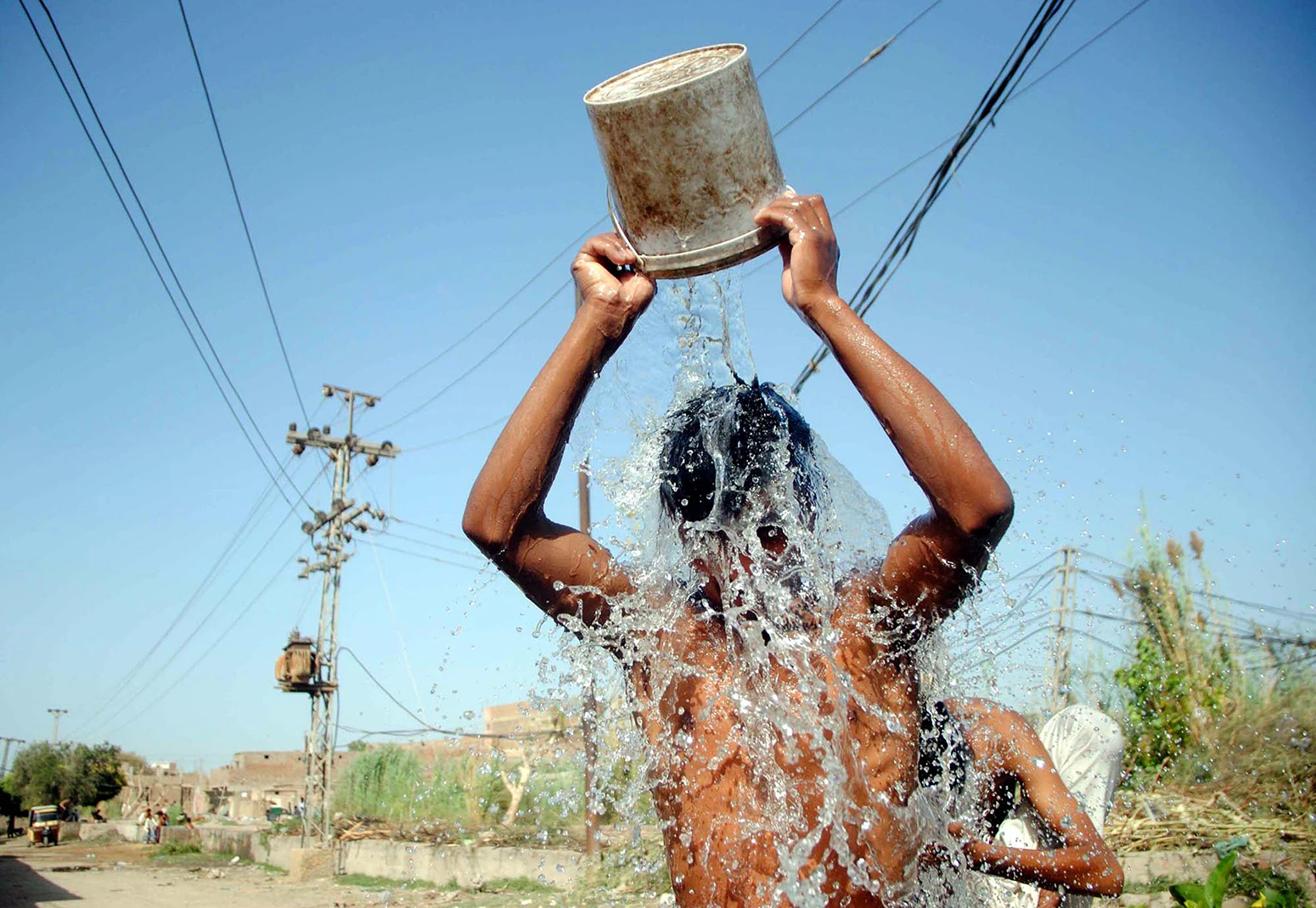 En ung man häller vatten över sig själv under en värmebölja i Hyderabad, Pakistan, den 4 april 2022.
