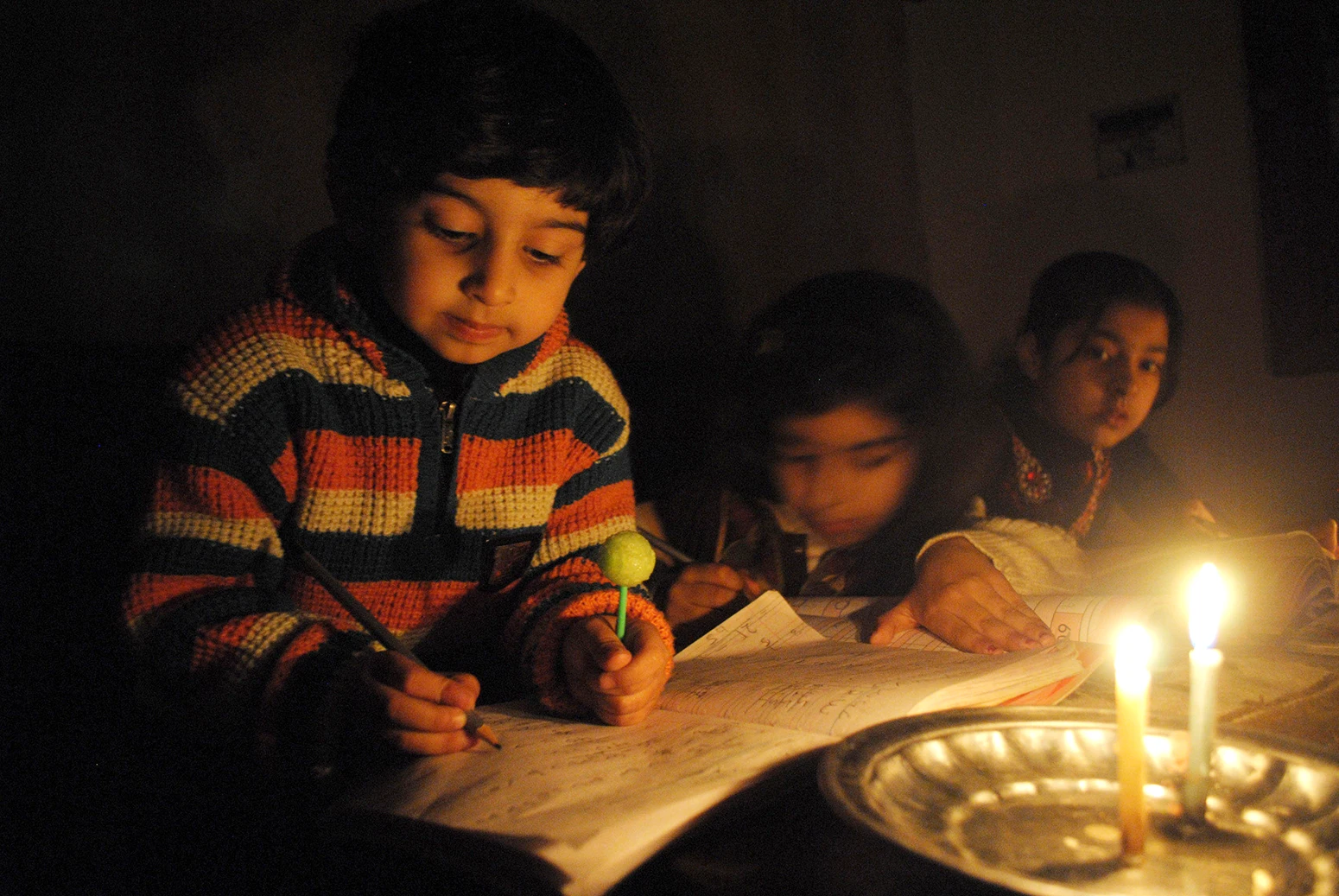 Los niños estudian a la luz de las velas durante un corte de energía en Peshawar, en el noroeste de Pakistán, en enero de 2015.
