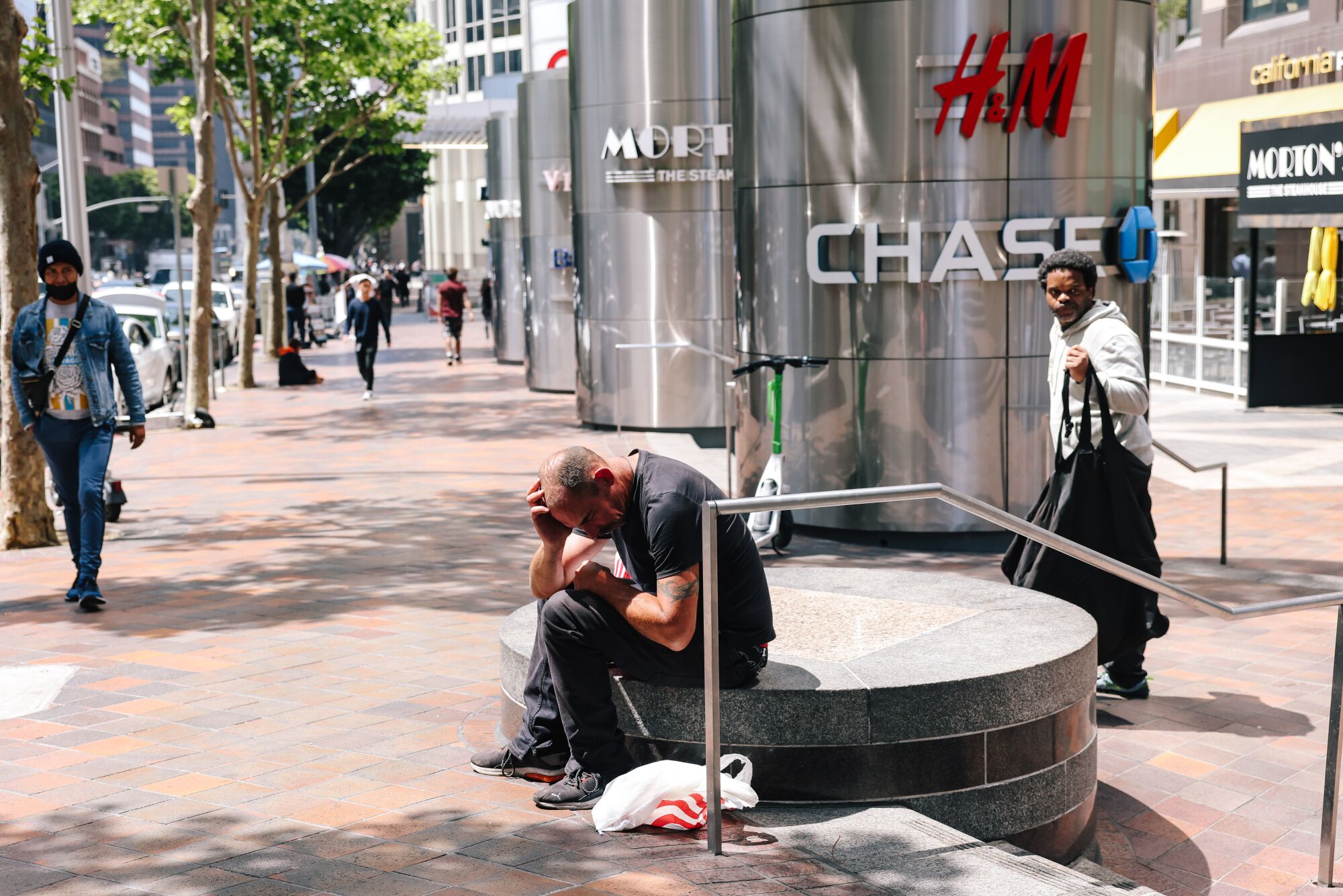 Un hombre descansa cerca de edificios de oficinas y un centro comercial al aire libre en el distrito financiero del centro.
