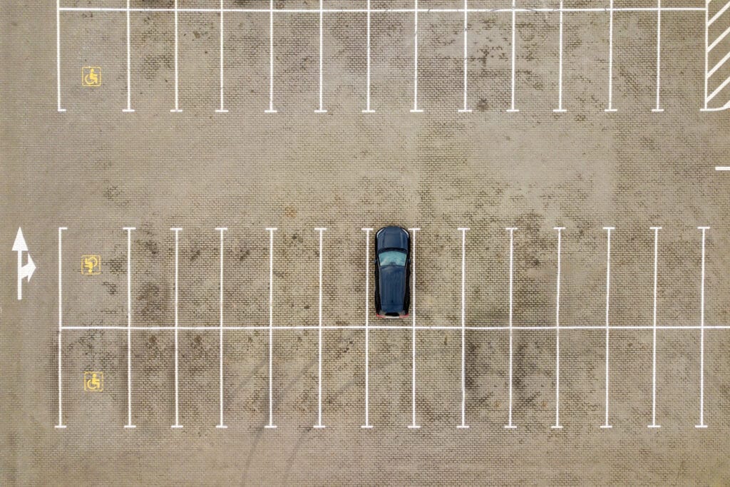 Vista aérea de arriba hacia abajo de muchos autos en un estacionamiento de supermercado o en el mercado de venta de autos.