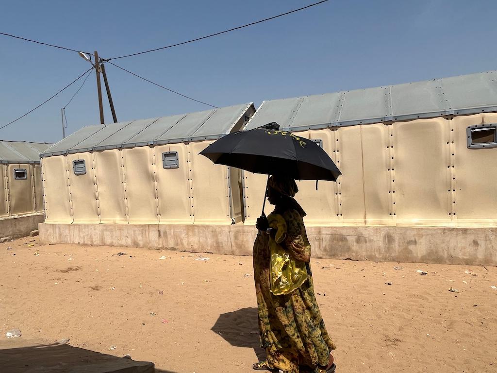 La vendedora de pesca Khady Beye Sene usa un paraguas para protegerse del calor del mediodía en la ciudad de tiendas de campaña de Diougoup en St. Louis, Senegal, el 31 de octubre de 2022.