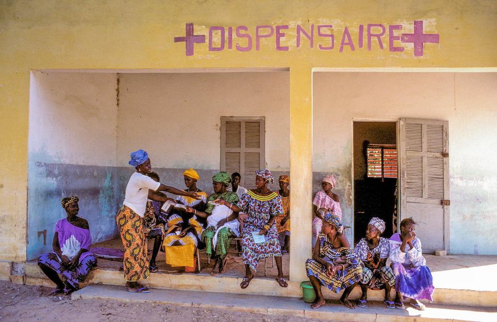 Women wait outside a clinic with their children in Thies, Senegal. 